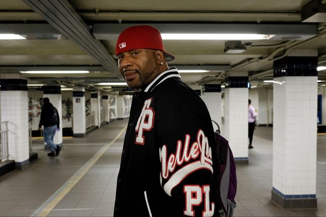 A man in a red baseball cap stands in subway station